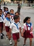 Children marching down the street in their school uniforms.