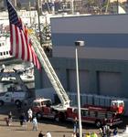 A huge American flag waved from the ladder of a firetruck.