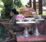 A woman sits next to the days offerings.