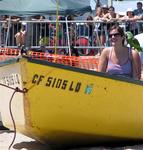 A female volunteer is ready to get pulled down the beach by a strongman.