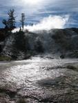 The air is warm and moist around the geothermal features.
